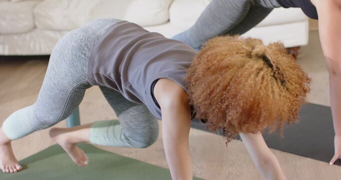 Two women following guided routine, drawing knee, rising to lunge on mats at home for strength
