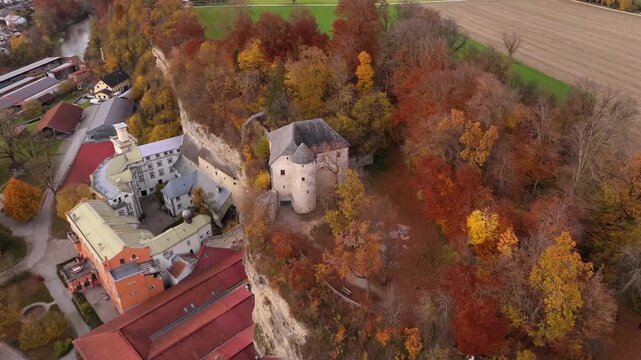 Scenic aerial of Schloss Stein an der Traun, Bavaria, Germany. Historic fortress on Nagelfluhwand above Traun valley surrounded by golden autumn trees. Luftaufnahme von Schloss Stein an der Traun 