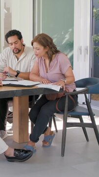 Vertical video: Receiving documents, woman in mauve blouse reviewing binder at table, for signing