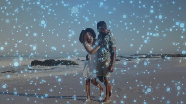Vertical video: Entering frame couple walking shore blue bokeh overlaying linking arms for travel