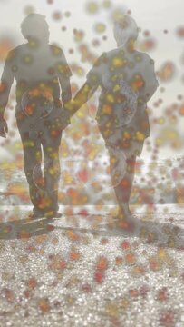 Vertical video: Senior duo walking holding hands on wet sand sun backlighting, health spots growing