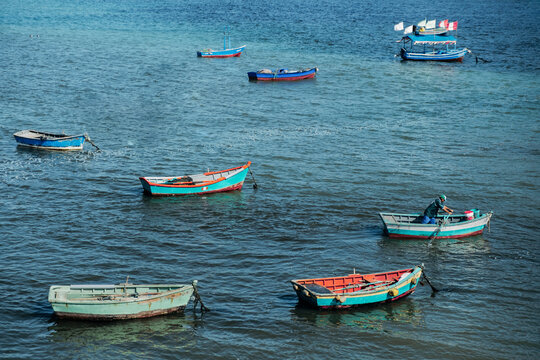 Peruvian fisherman rowing boat among colorful vessels