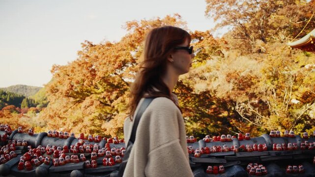 Woman walking past daruma dolls at japanese temple in autumn