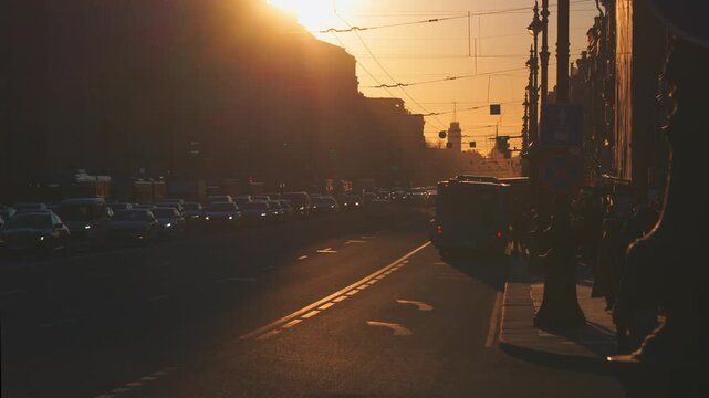 Saint-Petersburg, Russia - April 10 2026, 4k, panoramic view of Nevsky Prospect, cars on road, people walking on sidewalk, at sunset with bright sun, everything in orange light, St Petersburg, Russia