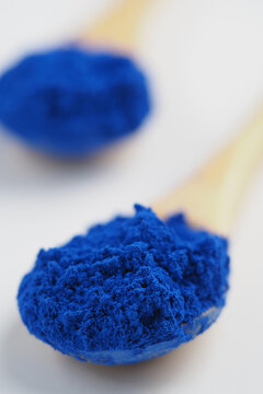 Bright blue nila powder sits on a wooden spoon 