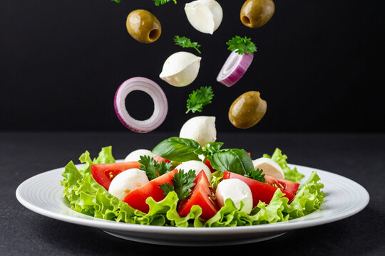 Fresh salad components tumble mid-air above a crisp base.