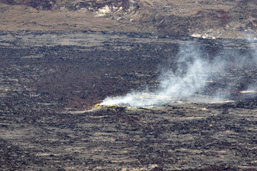 Naklejka premium Volcanic gas and steam rising from a yellow sulfur vent on the basalt floor of Hawaii Volcanoes National Park Big Island Hawaii