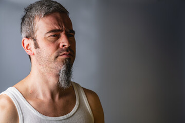 Serious bearded man with glasses studio portrait collection Man with a beard stands against a gray background and looks to the side © mykhailo