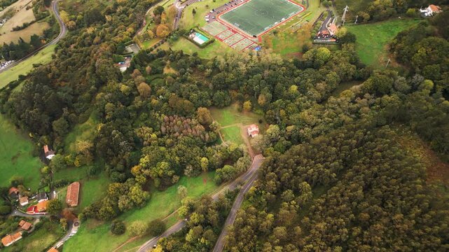 Epic San Miguel de Lillo church top down aerial panorama. 
Cinematic drone descending spiral flight over ancient historic 
pre-romanesque chapel, green park trees, winding road in Oviedo Spain.
