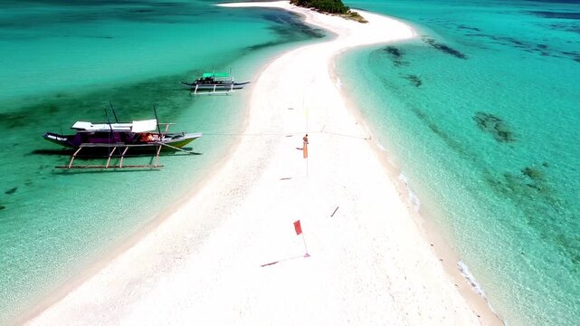 Aerial drone view of traditional outrigger boats anchored on a pristine white sandbar.