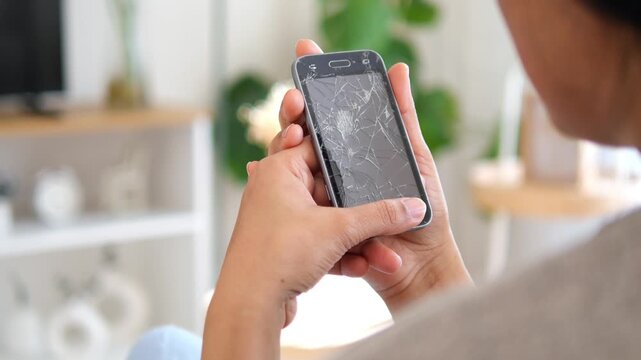 rear view of woman holding a broken smart phone sitting on a sofa 