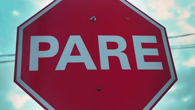 Foreground focus on a bright red PARE stop sign