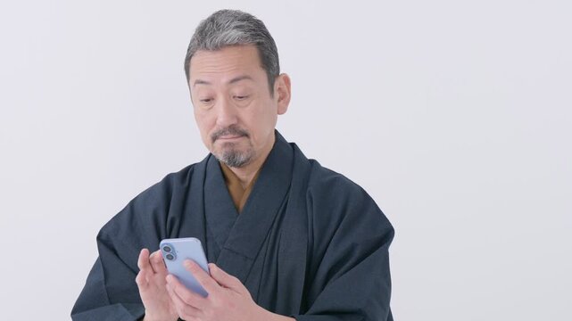 着物を着たスマホを使うシニア男性