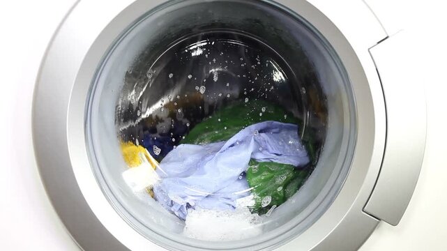 closeup working laundry machine spinning cleaning colorful cloth colored tumbling clothing soap