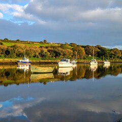 Fototapeta premium A serene lake scene with boats and a cloudy sky reflected