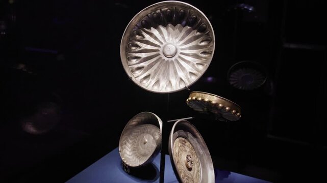 Collection of ancient Egyptian faience bowls with radial and geometric patterns, showcased in a dark museum exhibition with reflective glass and curated lighting.