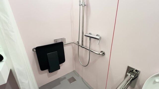 Camera moves from top to bottom showing a fully equipped accessible shower with grab bars and seating. Concept for accessibility, hygiene, and patient care.