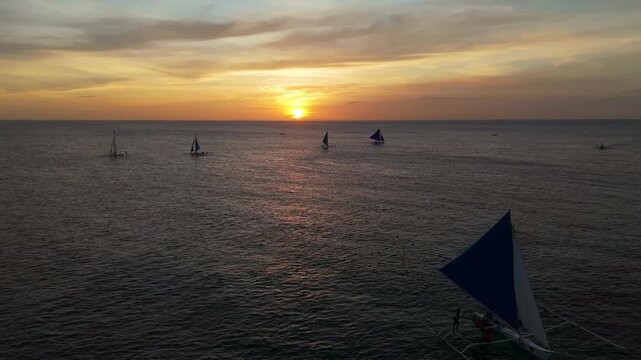 Aerial view of Dozens of traditional boats gather on the calm ocean during sunset in Boracay Island, Philippines