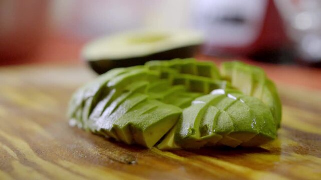 A closeup shot of a perfectly sliced ripe avocado sitting on a rustic wooden cutting board, ideal for healthy eating and culinary content.