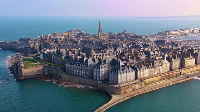 Saint Malo Intra Muros in Ille et Vilaine Brittany France with fortified granite walls enclosing dense urban fabric and Saint Vincent Cathedral spire above English Channel waters, establishing shot