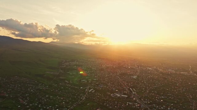 Aerial drone view of Telavi, Georgia, featuring the city framed by the Caucasus mountain range and surrounding regional landscape in clear daylight.