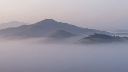 Fototapeta premium Misty mountain ridges emerging above low morning fog