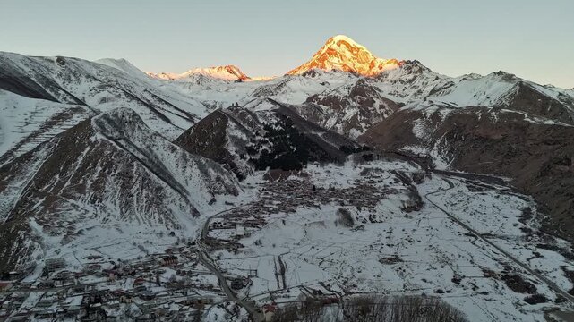 cinematic drone shot moves forward slowly toward the snow-capped peak of Mount Kazbek in the Caucasus Mountains, Georgia