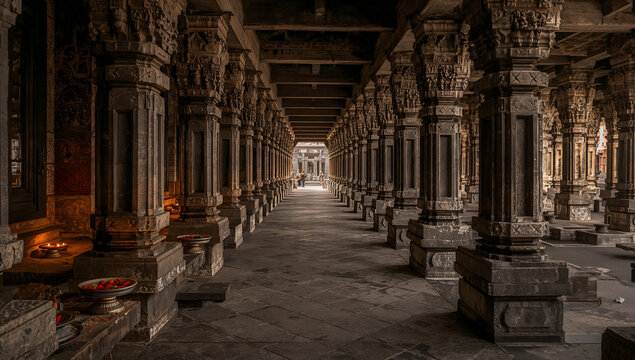 Ancient temple colonnade with intricately carved stone pillars, dimly lit corridor with a spiritual atmosphere, stone carving