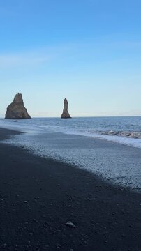 Dramatic black sand beach of Reynisfjara with basalt columns and sea stacks, South Iceland

