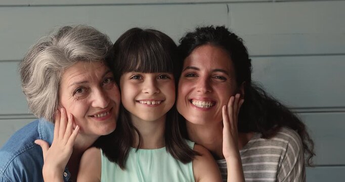 Closeup smiling granddaughter posing for family portrait with adult mother and grandmother, showing unity, bonding, tenderness between multigenerational relatives, intergenerational connection concept