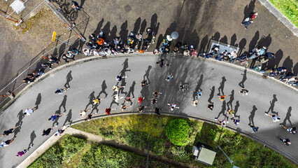 Obraz premium Aerial drone view of people running half marathon race in city, shadows of runners on road racing sport competition, top-down view of athletes and spectators, Venlo, the Netherlands