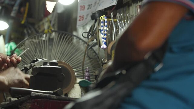 Craftsman sharpening a nail cleaner while customer observes