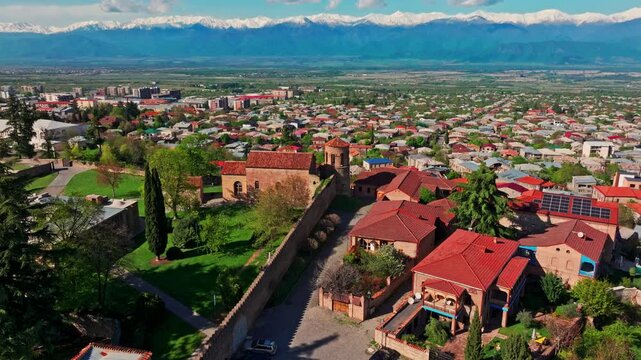 Drone shot over Telavi, Georgia, capturing the cityscape set against the dramatic backdrop of the Caucasus mountains from above.