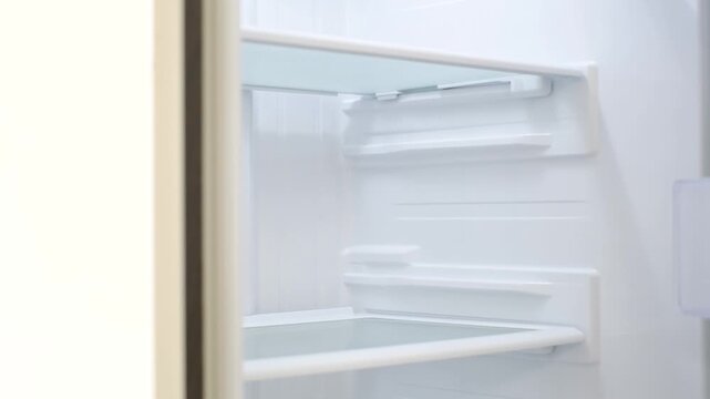 Modern open refrigerator close-up with empty shelves, side view.