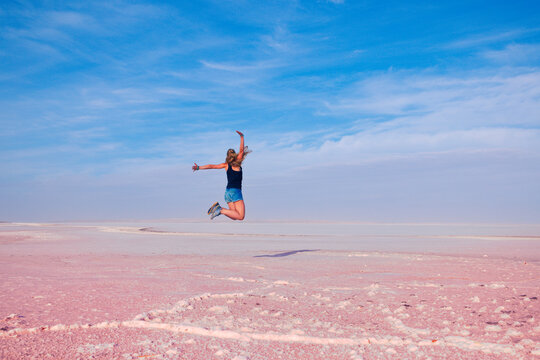 Successful Woman Jumping for Joy on Pink Salt Lake Landscape