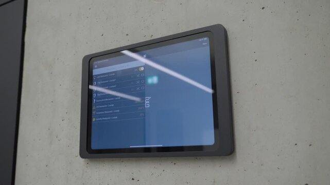 A static shot of a tablet interface mounted on a concrete wall for managing building lights.