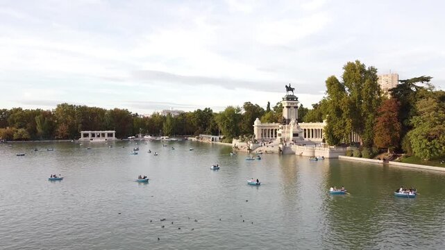 Aerial view of tourists on boats enjoying an autumn day on a great pond in front of monument to Alfonso XII at the Retiro Park (Parque del Buen Retiro) in Madrid, Spain.