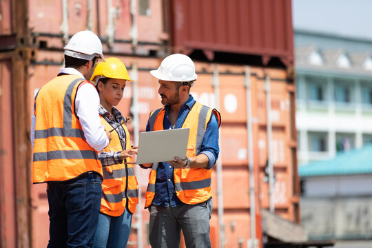 Hispanic man harbor worker talking on the walkie-talkie radio and control loading containers at container warehouse. container yard port of import and export goods