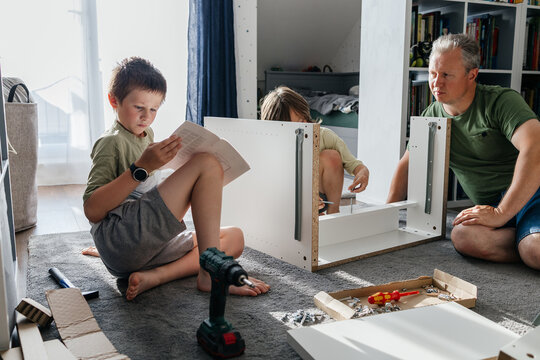Father and sons assembling furniture, teamwork bonding moment