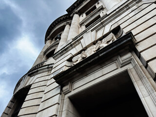 Naklejka premium Historic stone building facade with columns and carved emblem on Hanover Street, Edinburgh, Scotland, UK, dramatic cloudy sky and upward perspective