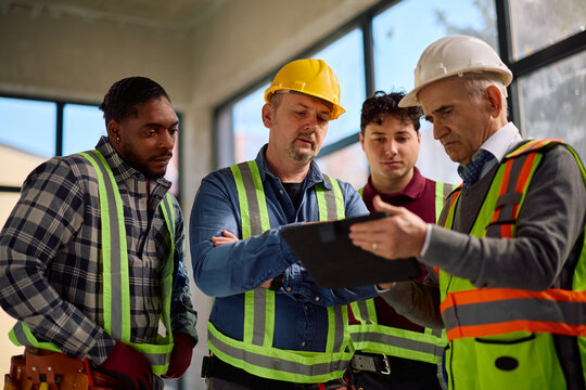 Construction workers and architect working on digital tablet during rebuilding project on site.