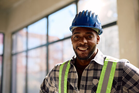 Portrait of happy black worker at construction site looking at camera.