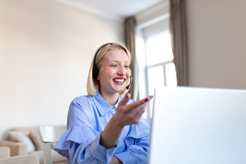 Cheerful customer support agent. Smiling young blonde woman wearing a headset and blue striped...