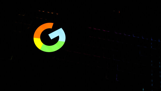 Colorful Google "G" Icon Glowing Vibrantly on a Smartphone Screen Against a Dark Backlit Gaming Keyboard - Concept for Modern Search Engines, Digital Tech Trends, and Online Data Connectivity