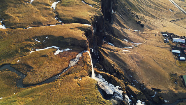 River course flowing among hills in iceland, natural foss a sidu waterfall in icelandic scenery. Spectacular cascade falling off from scandinavian cliffs. Slow motion. Drone shot.