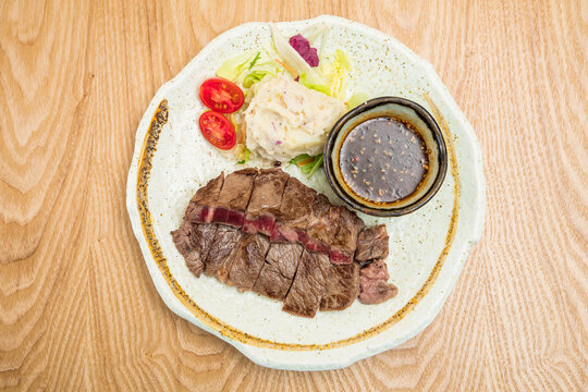 Sliced beef steak with salad and sauce