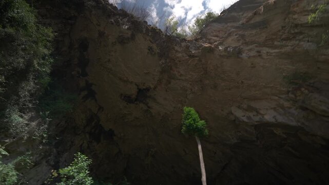 Tilt up reveal and pan across underneath the entrance to Nam Non Cave in Laos