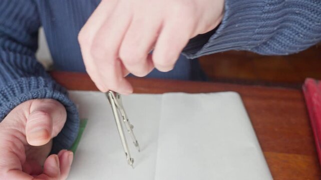 Medium shot of hands using a compass to draw a precise circle, emphasizing accuracy, technical skill, and geometric design work.