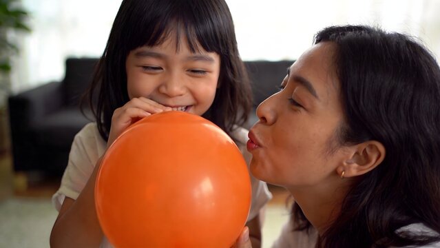 Woman and child blowing orange balloon