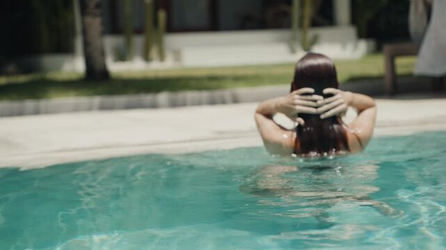 Woman emerging from the water in a luxury swimming pool